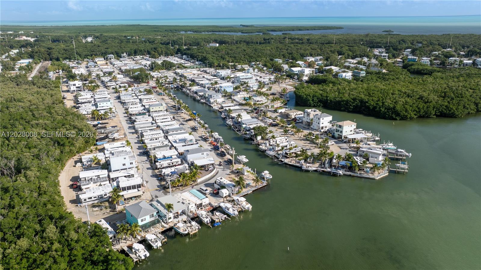 An aerial view shows a coastal community with mobile homes, boat slips, and surrounding mangroves — 325 Calusa Street, Key Largo FL 33037, KEY LARGO, FL