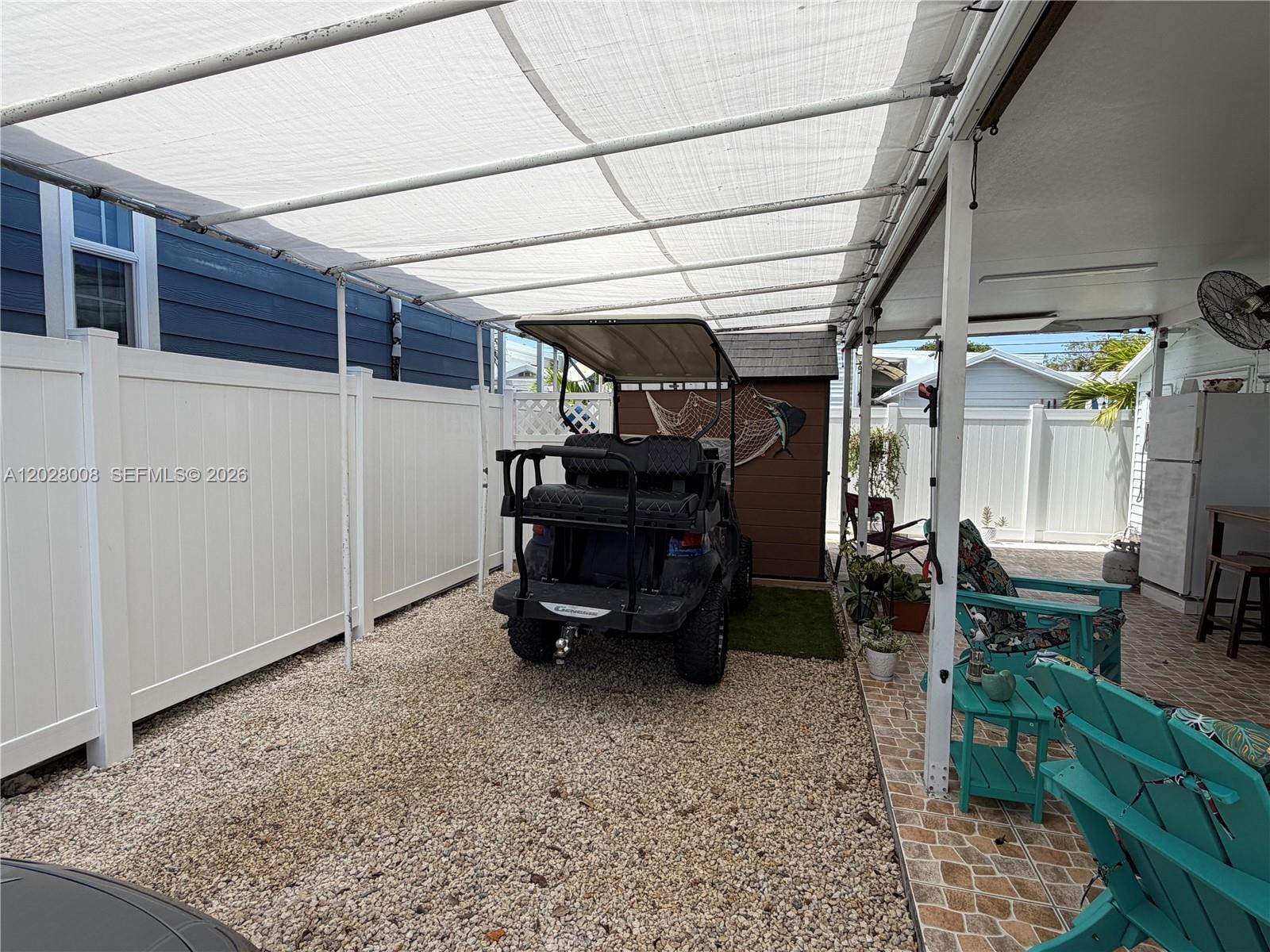 A golf cart is parked on a gravel patio under a white fabric canopy — 325 Calusa Street, Key Largo FL 33037, KEY LARGO, FL