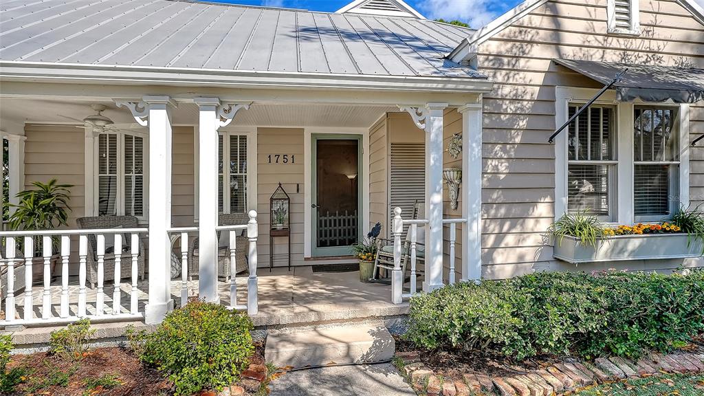 The exterior of a house features a covered front porch with white railings and columns — 1751 FLOYD STREET, SARASOTA, FL