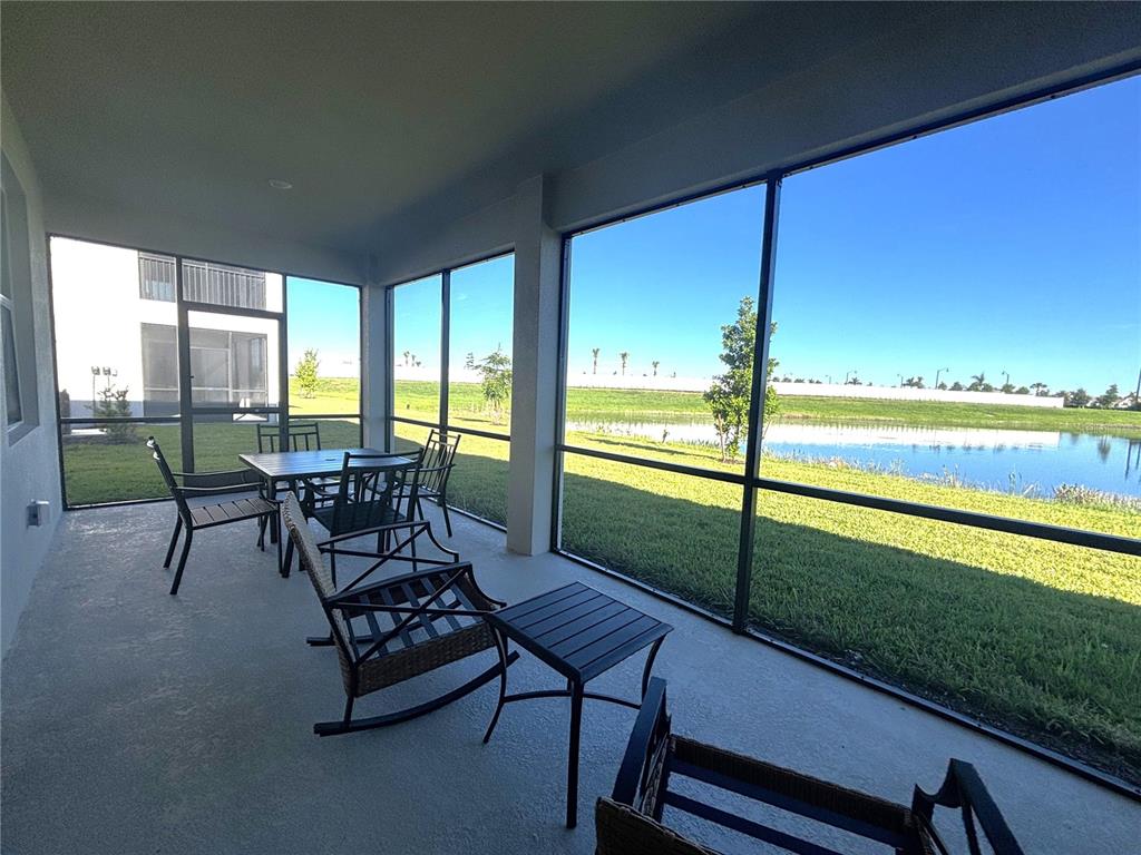 A screened-in patio features outdoor furniture overlooking a grassy lawn and a small pond — 17745 BORACAY COURT UNIT 101, VENICE, FL