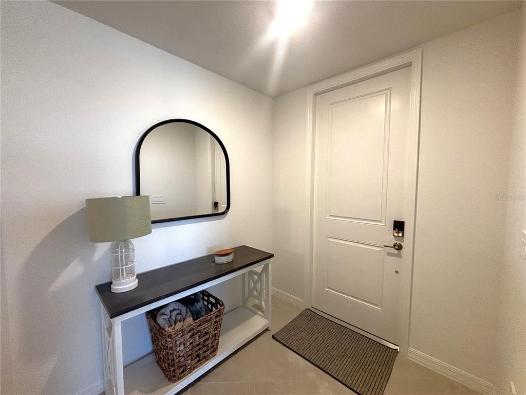 An entryway features a console table with a lamp, a mirror, and a front door — 17745 BORACAY COURT UNIT 101, VENICE, FL