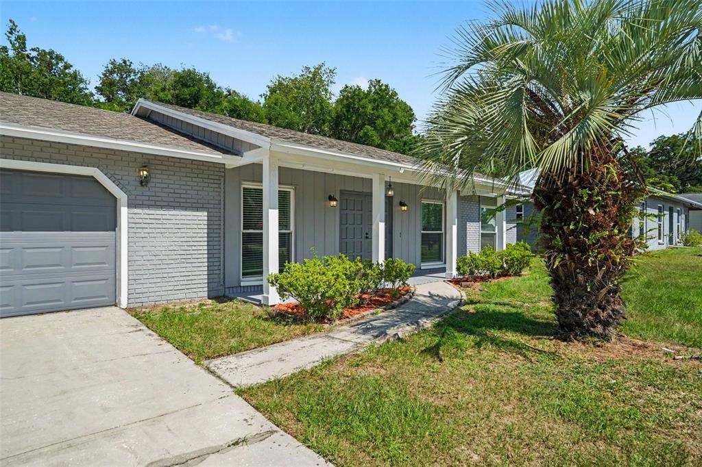 A single-story gray house with a garage, a front porch, and a palm tree — 3607 WOODHILL DRIVE, BRANDON, FL