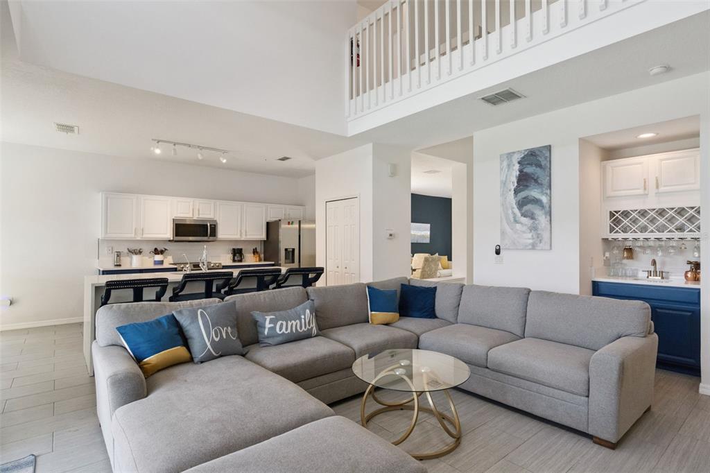 A living room with a large gray sectional sofa, open kitchen, and a wet bar — 652 HIGHGATE PARK BOULEVARD, DAVENPORT, FL