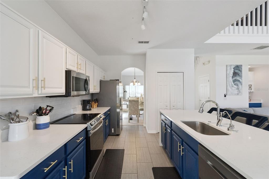 A kitchen features white upper cabinets, blue lower cabinets, white countertops, and stainless steel appliances — 652 HIGHGATE PARK BOULEVARD, DAVENPORT, FL