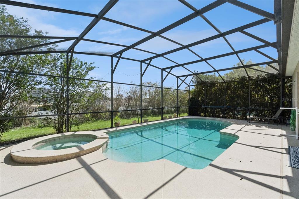 A screened-in swimming pool and spa with a concrete deck under a metal frame — 652 HIGHGATE PARK BOULEVARD, DAVENPORT, FL