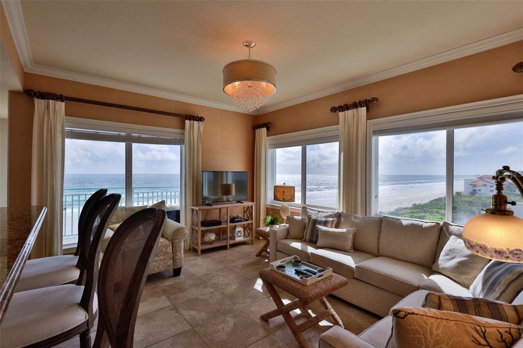 A living room with tile floors, a sectional sofa, and floor-to-ceiling ocean views — 2801 HILL STREET UNIT 502, NEW SMYRNA BEACH, FL