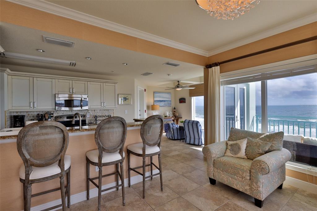 A kitchen with bar seating overlooks a living area and a balcony with ocean views — 2801 HILL STREET UNIT 502, NEW SMYRNA BEACH, FL