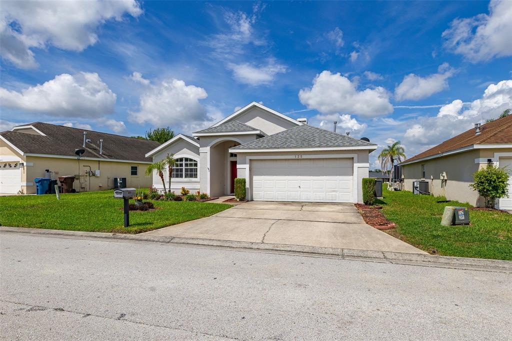A single-story suburban house with a two-car garage and a concrete driveway — 135 JESSAMINE DRIVE, DAVENPORT, FL