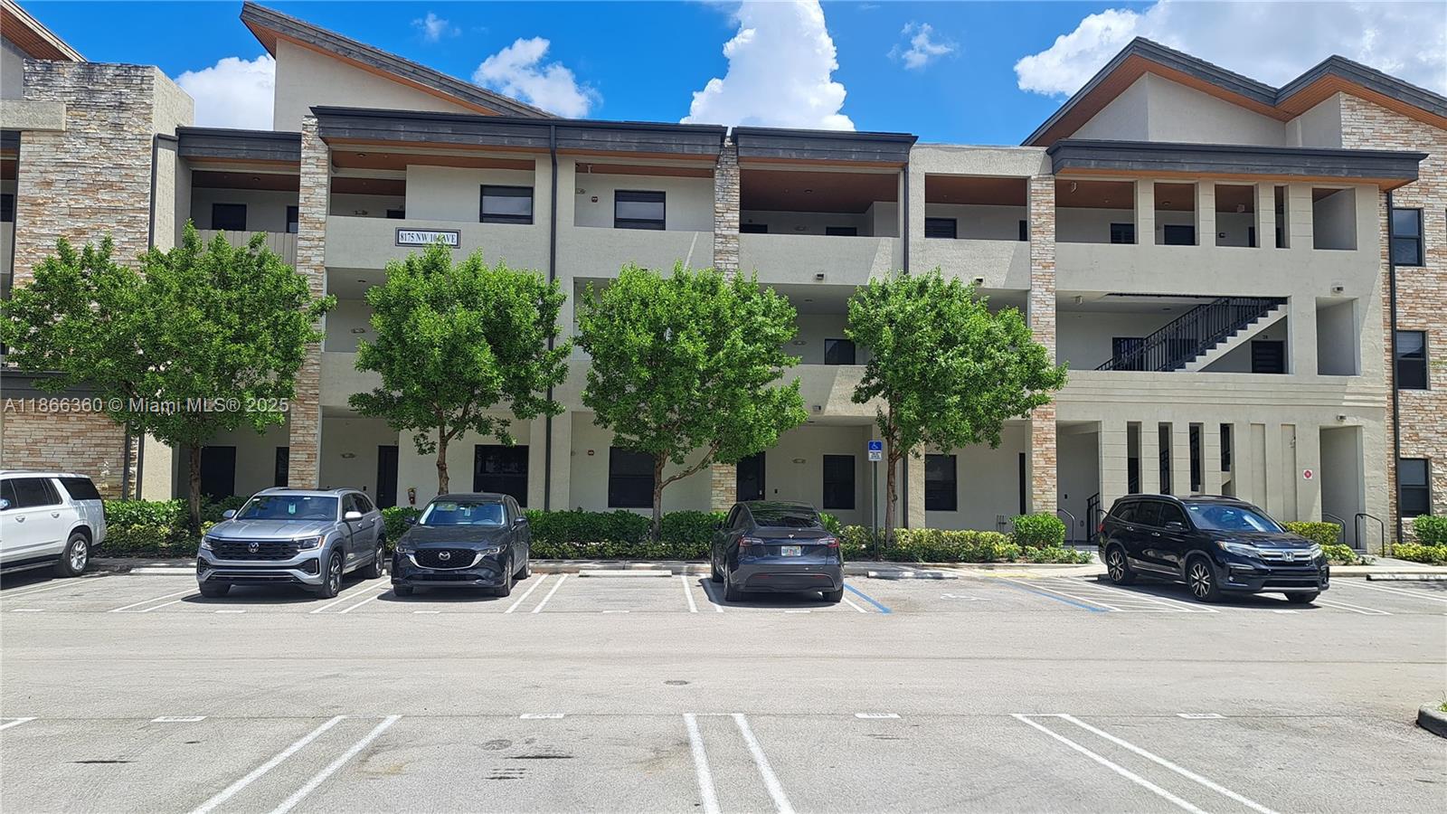 A three-story apartment building features a tan stucco facade with stone accents and parking spaces — 8175 NW 104th Ave # 35, Doral FL 33178, DORAL, FL