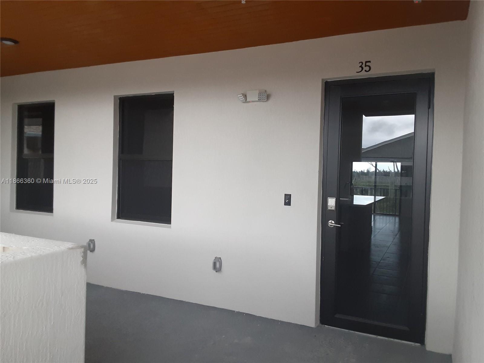 A white exterior wall features two windows, a dark glass door numbered 35, and lighting — 8175 NW 104th Ave # 35, Doral FL 33178, DORAL, FL