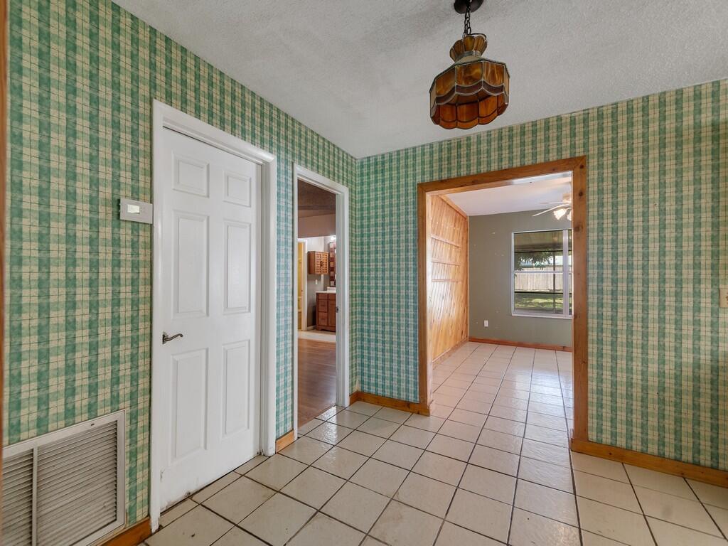 A tiled entryway features green plaid wallpaper, a vintage pendant light, and two doorways — 2309 NE 13th Court, Jensen Beach FL 34957, JENSEN BEACH, FL