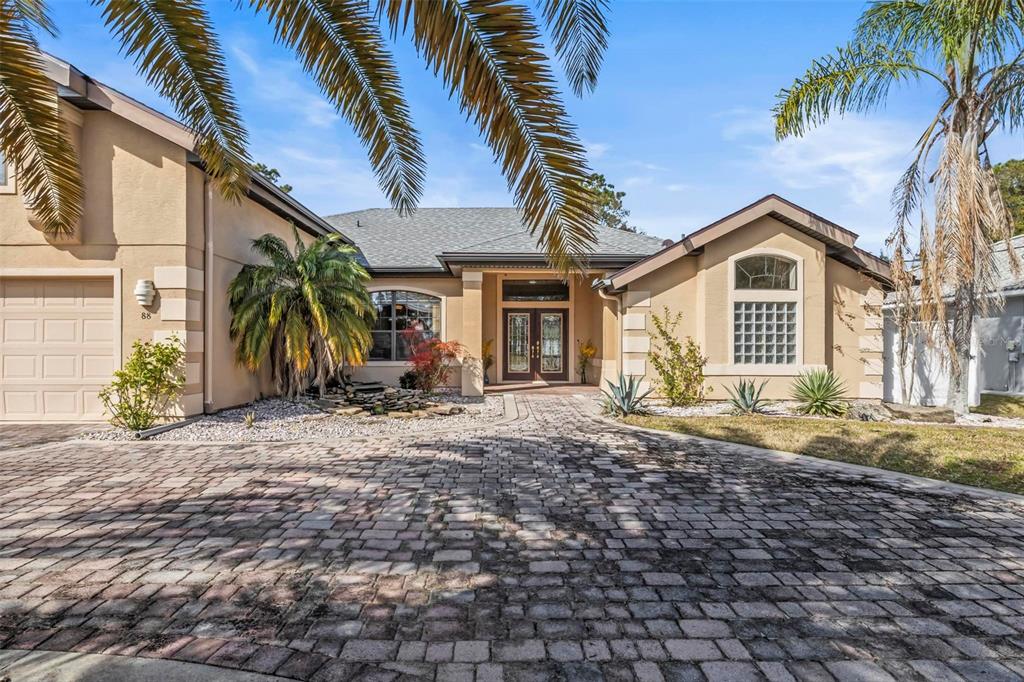 A single-story house with a paved driveway, palm trees, and a double-door front entrance — 88 COVINGTON LANE, PALM COAST, FL