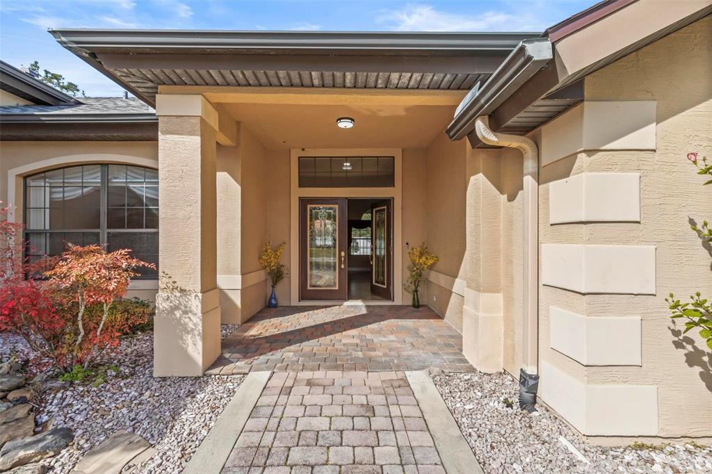 A paved walkway leads to the covered entryway of a house with double glass doors — 88 COVINGTON LANE, PALM COAST, FL