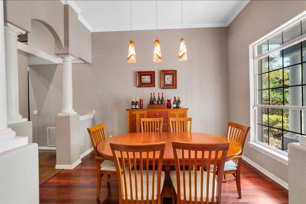 A dining room features a round wooden table, six chairs, a sideboard, and pendant lighting — 2304 INDIAN MOUND TRAIL, KISSIMMEE, FL