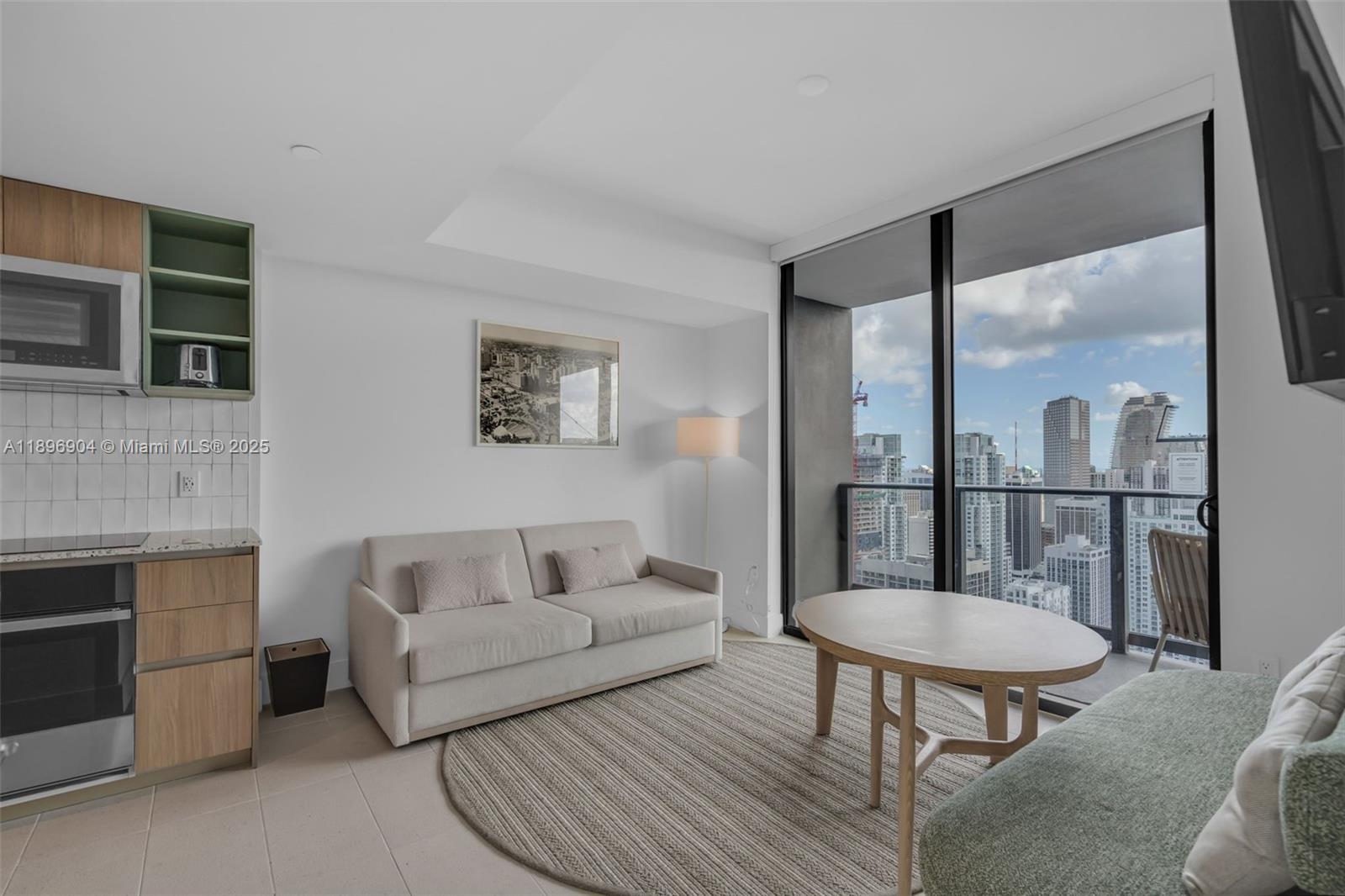 A modern studio apartment features a kitchenette, a sofa, a coffee table, and city views — 159 NE 6th St # 4514, Miami FL 33132, MIAMI, FL