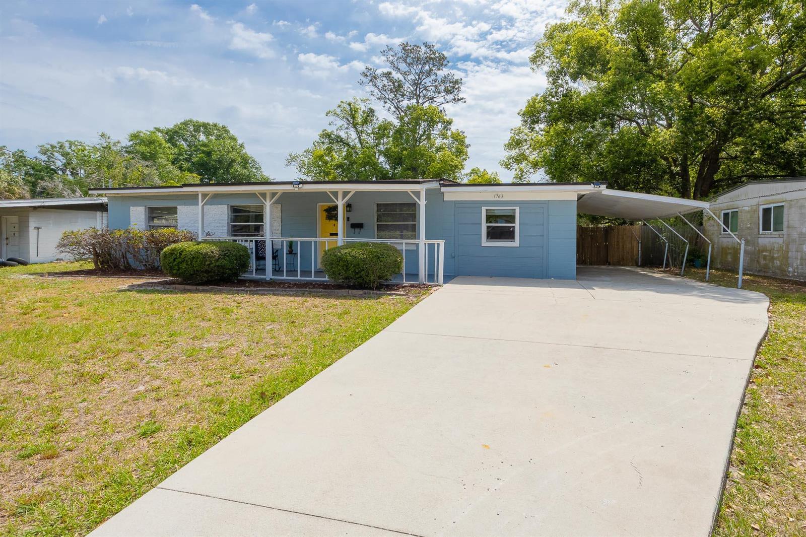 A blue single-story house features a front porch, a concrete driveway, and a carport — 1763 Lawson Road, Jacksonville FL 32246, JACKSONVILLE, FL