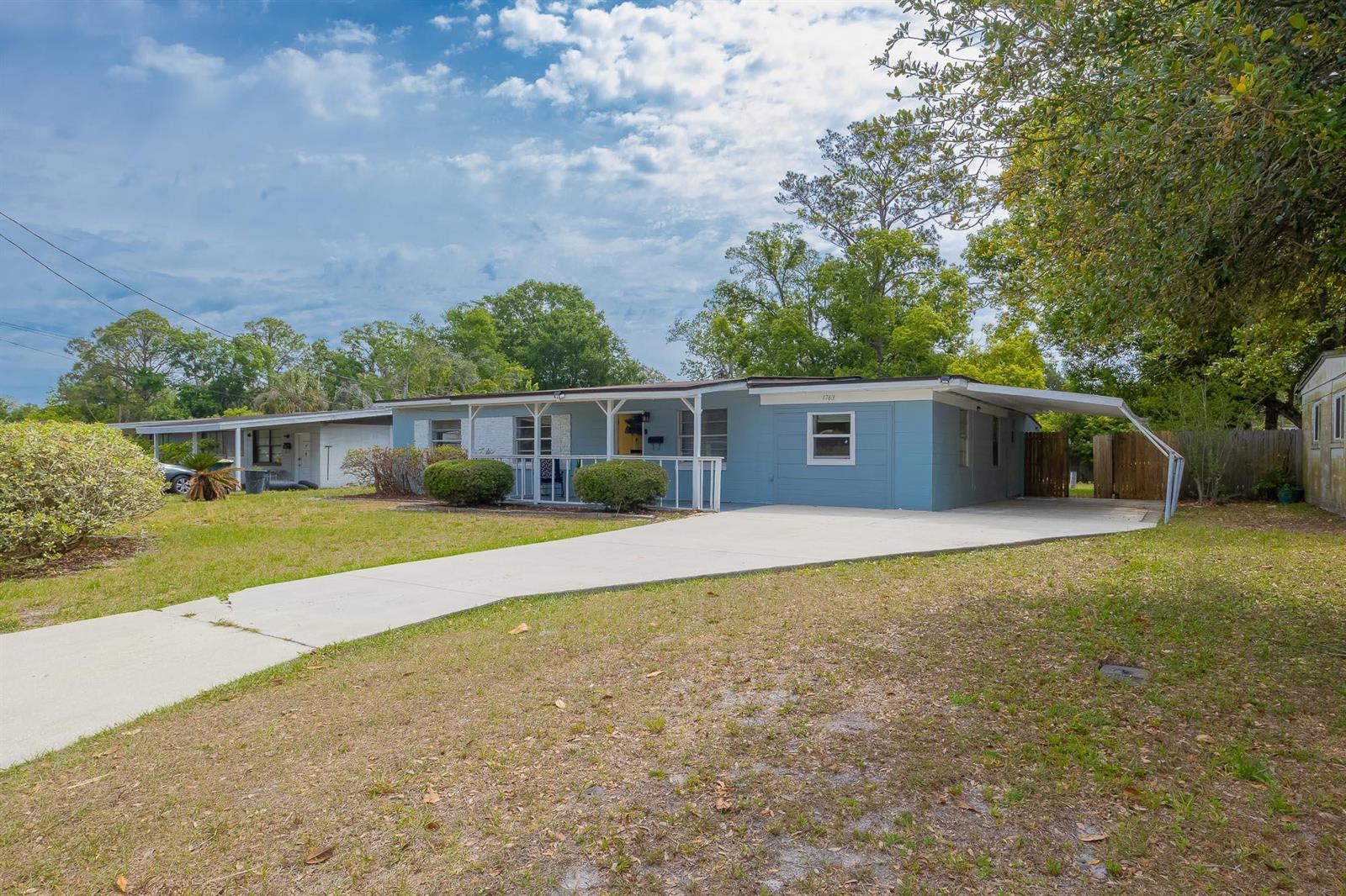 A light blue single-story house features a concrete driveway, a covered carport, and a porch — 1763 Lawson Road, Jacksonville FL 32246, JACKSONVILLE, FL