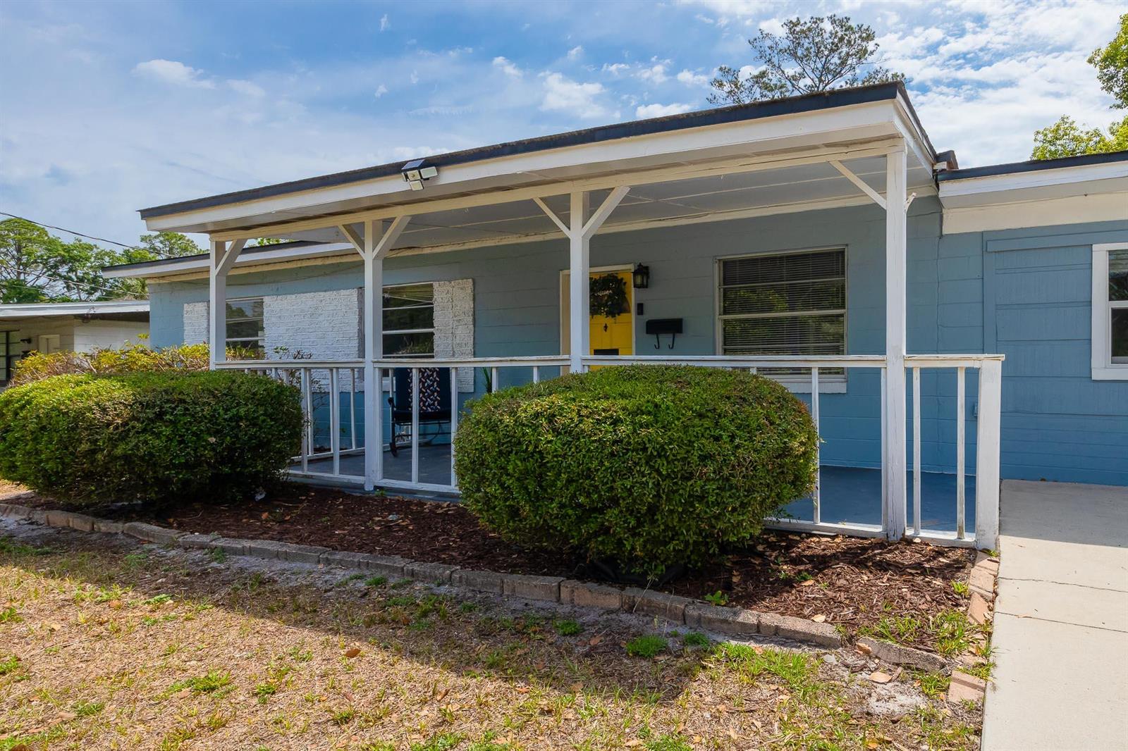 A light blue house features a covered front porch with white railings and landscaping — 1763 Lawson Road, Jacksonville FL 32246, JACKSONVILLE, FL