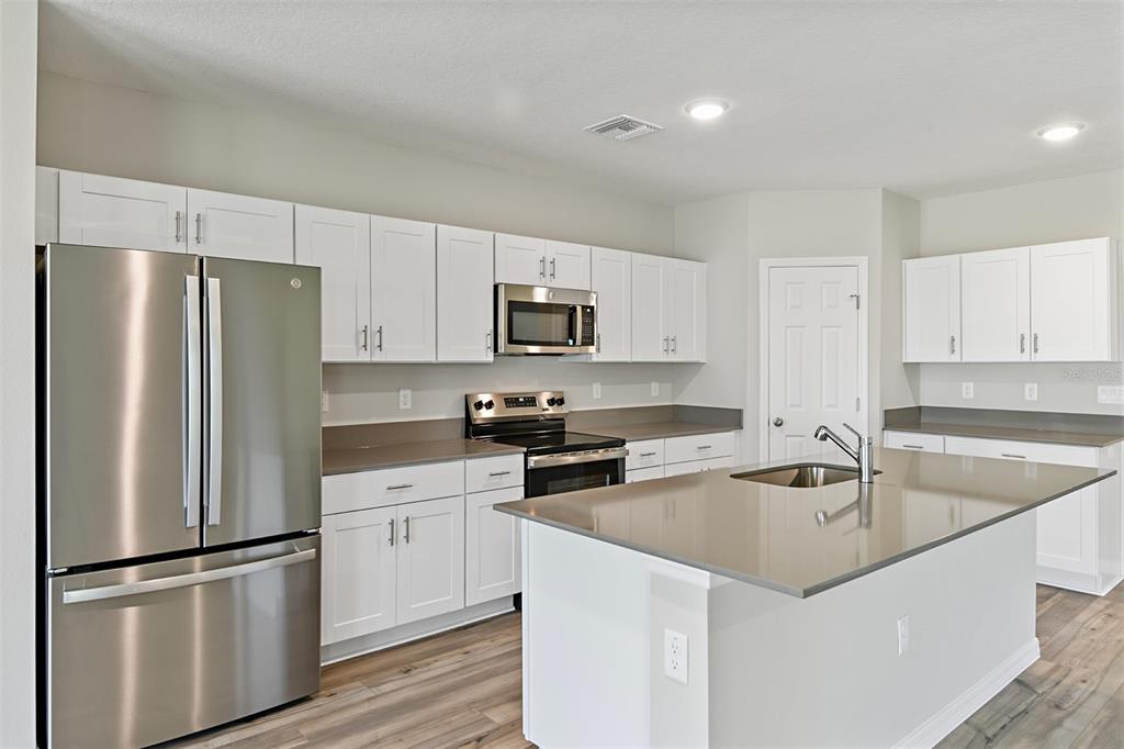A kitchen with white cabinets, stainless steel appliances, a center island, and gray countertops — 3911 ALTITUDE RUN, DAVENPORT, FL