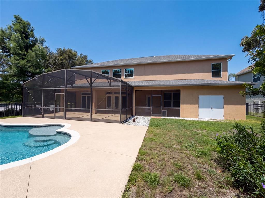 The backyard features a swimming pool, a screened-in patio, and a two-story tan house — 280 CHANDLER CIRCLE, OVIEDO, FL