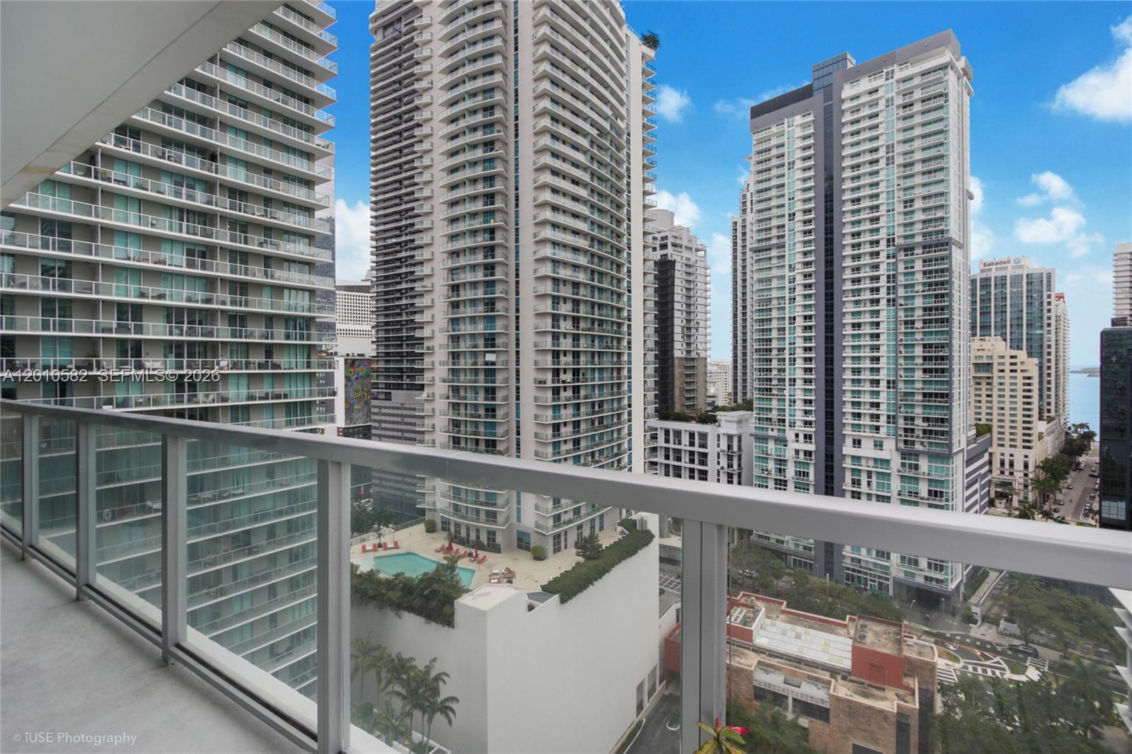 A high-rise balcony overlooks a dense urban landscape with multiple residential towers and a pool — 79 SW 12th St, Miami FL 33130, MIAMI, FL