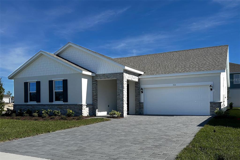 A single-story house with a stone facade, white siding, and a two-car garage — 733 FARFIELDS WAY, DELAND, FL
