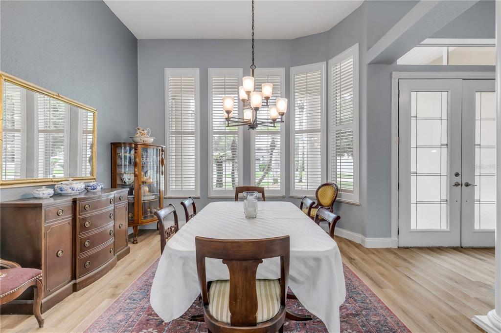 A dining room features a wooden table, chairs, a sideboard, and a chandelier under windows — 6095 SUMMERLAKE DRIVE, PORT ORANGE, FL