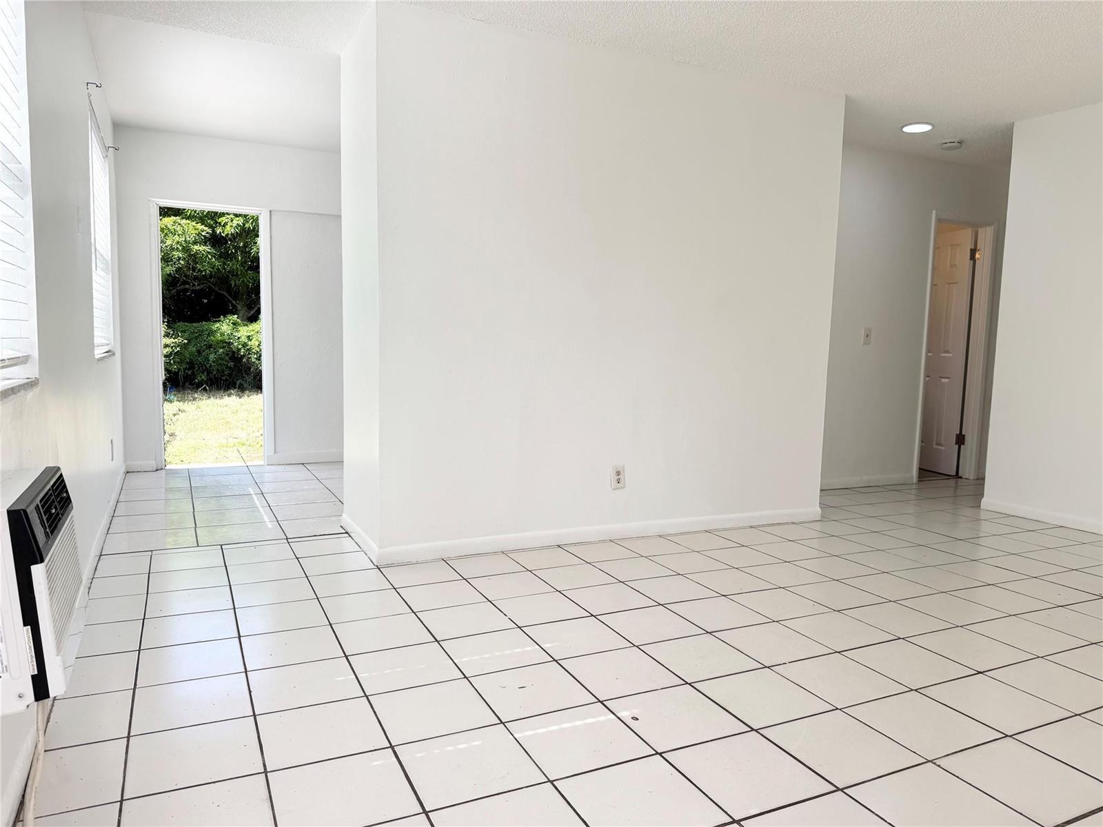 A bright, empty room features white walls, white tiled floors, and an open exterior doorway — 147 W 17th Street, Riviera Beach FL 33404, RIVIERA BEACH, FL