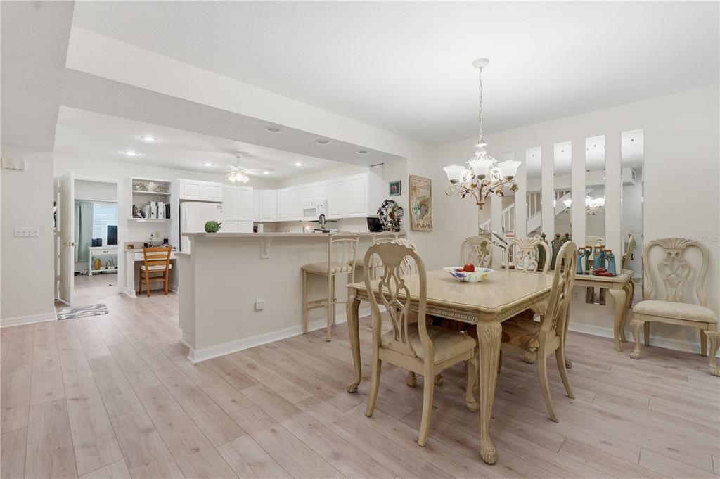 A dining area with a table and chairs sits adjacent to an open white kitchen — 545 PINELLAS BAYWAY S UNIT 302, ST PETERSBURG, FL