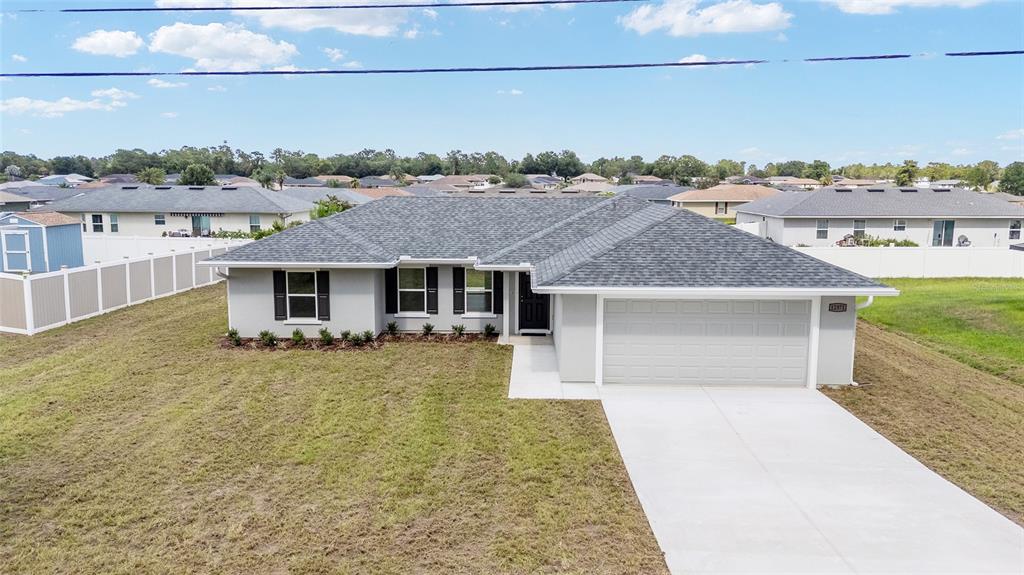 A single-story house with a gray roof, light gray exterior, and a concrete driveway — 12371 SE 100TH AVENUE, BELLEVIEW, FL