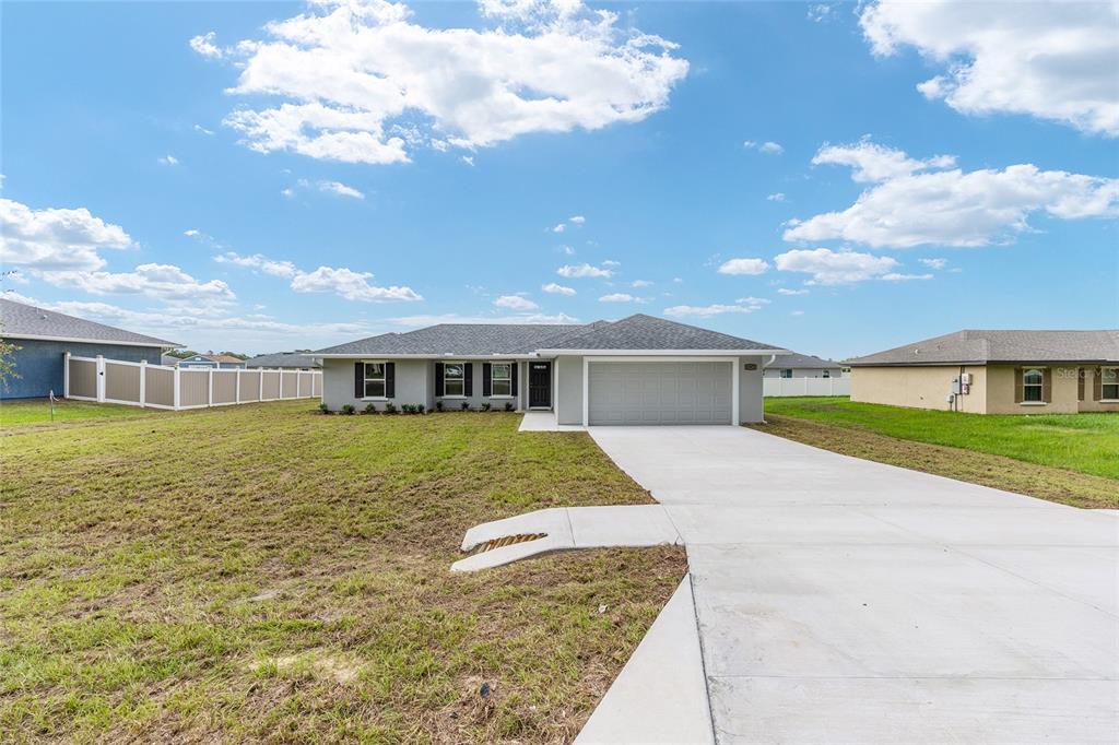 A single-story gray house with a two-car garage and a concrete driveway — 12371 SE 100TH AVENUE, BELLEVIEW, FL