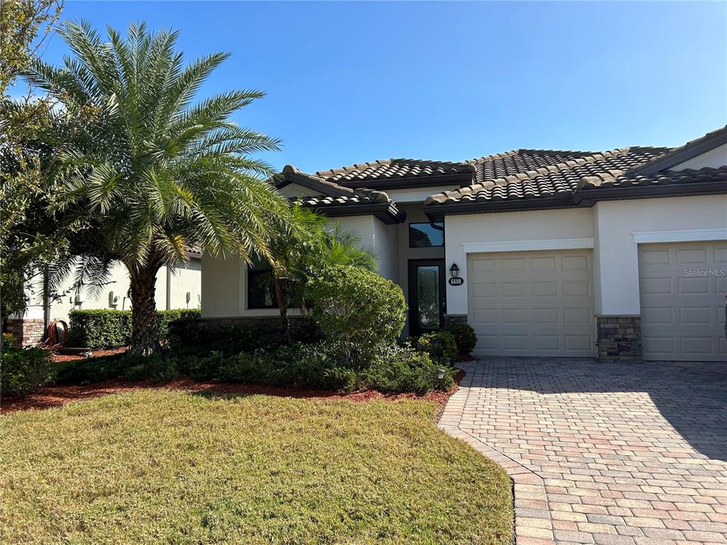A single-story house with a paved driveway, a palm tree, and a two-car garage — 6808 WILD LAKE TERRACE, BRADENTON, FL