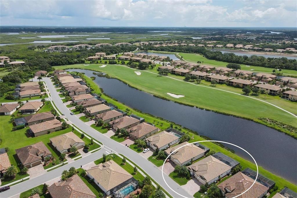 An aerial view shows a residential neighborhood with houses, a golf course, and a lake — 6808 WILD LAKE TERRACE, BRADENTON, FL