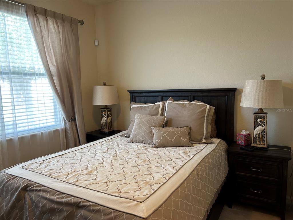 A bedroom features a bed with a dark wood headboard, two matching lamps, and curtains — 6808 WILD LAKE TERRACE, BRADENTON, FL
