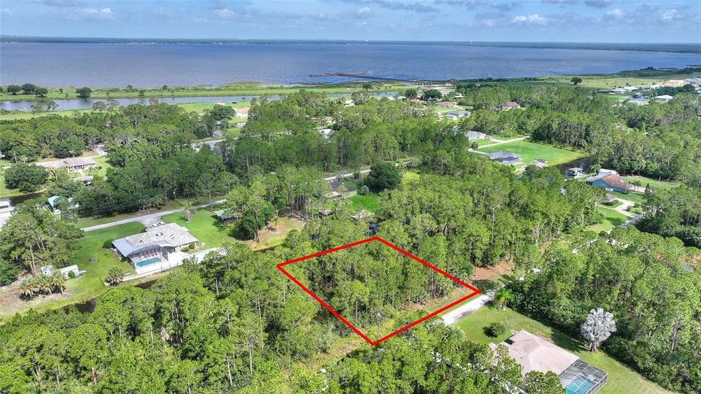 An aerial view shows a wooded residential lot outlined in red near a large lake — 25 AMARYLLIS DRIVE, INDIAN LAKE ESTATES, FL