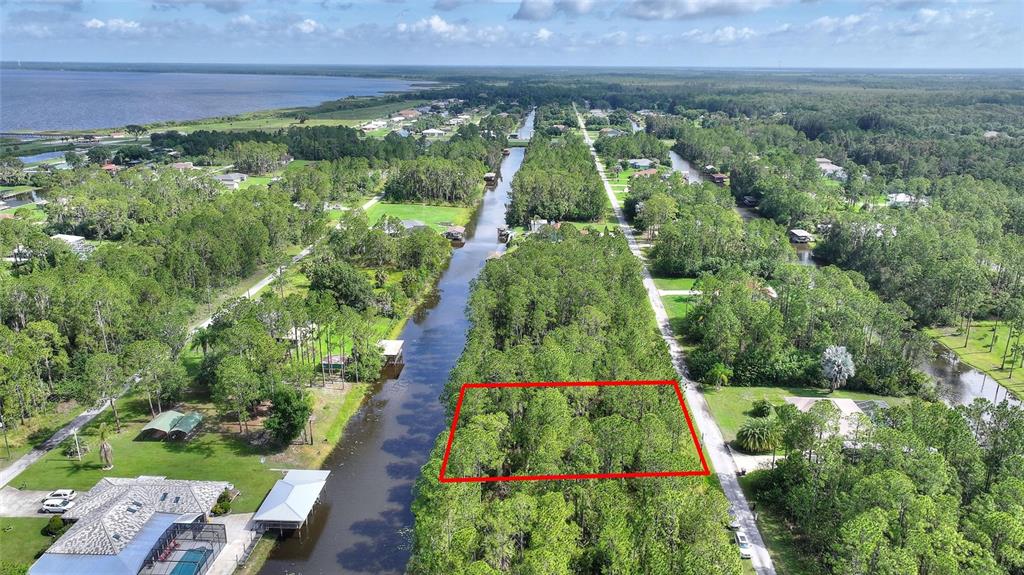 An aerial view shows a rectangular wooded lot outlined in red next to a canal — 25 AMARYLLIS DRIVE, INDIAN LAKE ESTATES, FL