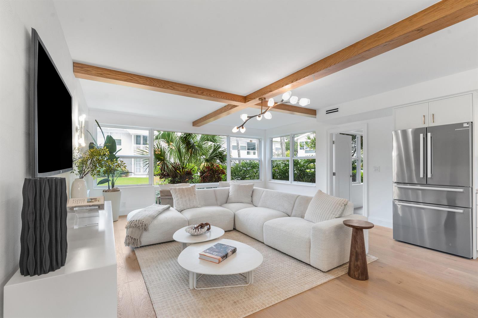 A bright living room features a white sectional sofa, wood ceiling beams, and large windows — 320 S Ocean Boulevard # c, Delray Beach FL 33483, DELRAY BEACH, FL