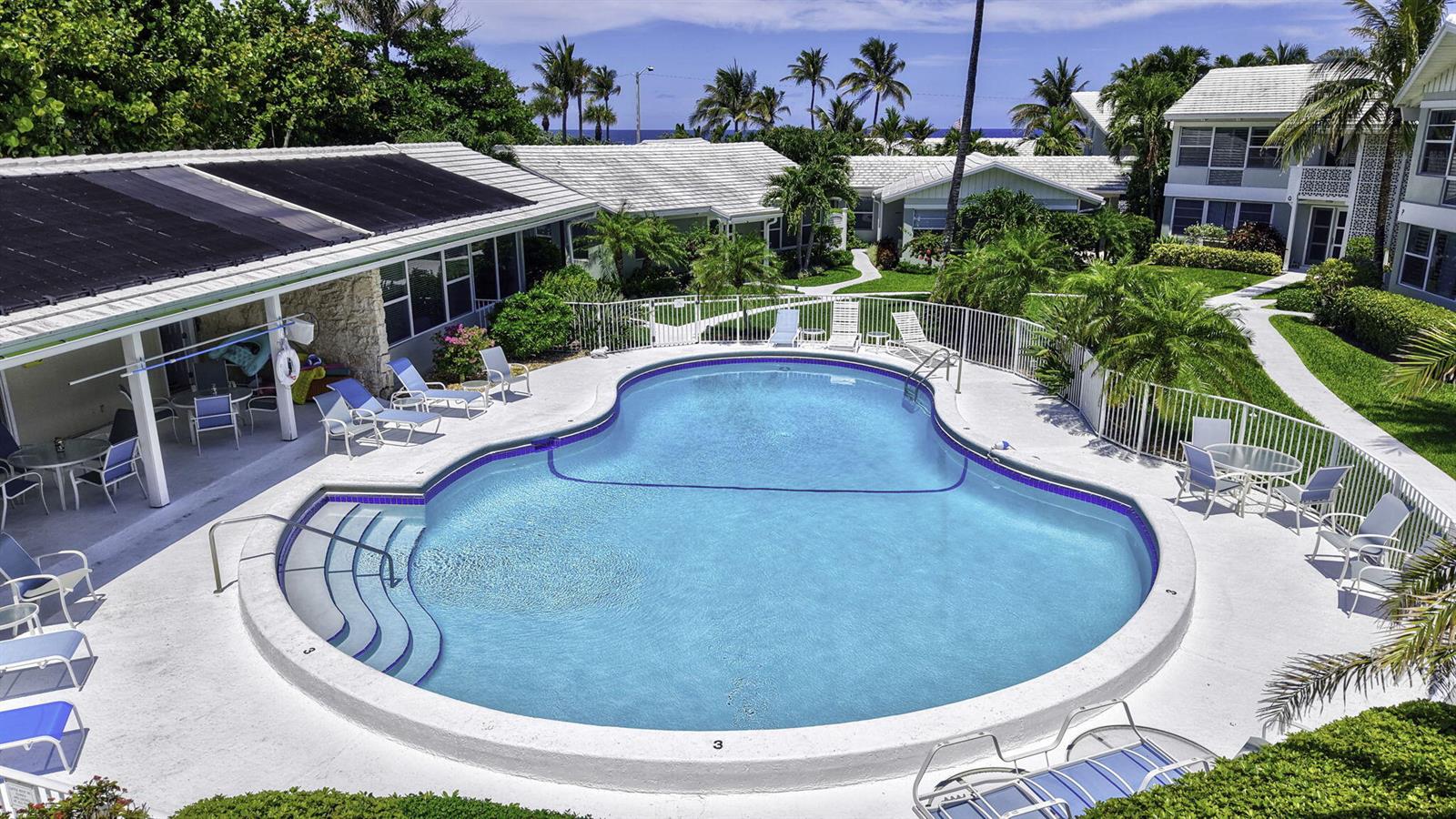 An outdoor swimming pool is surrounded by a patio, lounge chairs, and residential buildings — 320 S Ocean Boulevard # c, Delray Beach FL 33483, DELRAY BEACH, FL