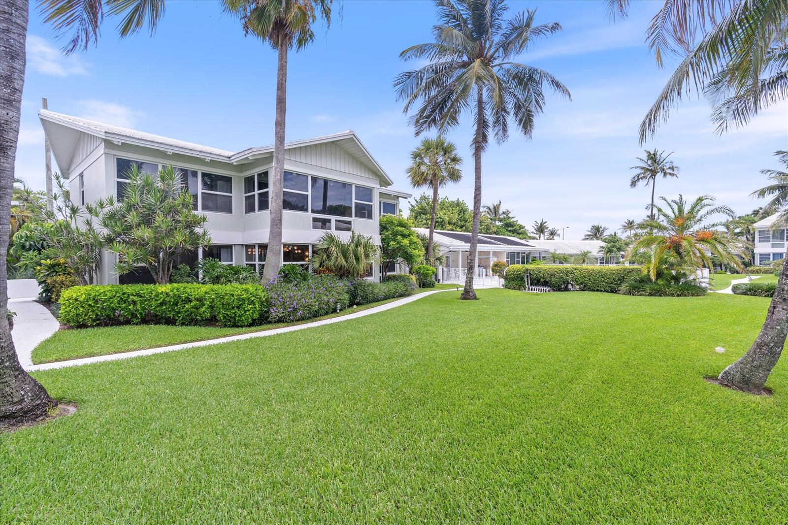 A two-story light-colored house sits behind a large green lawn with palm trees — 320 S Ocean Boulevard # c, Delray Beach FL 33483, DELRAY BEACH, FL