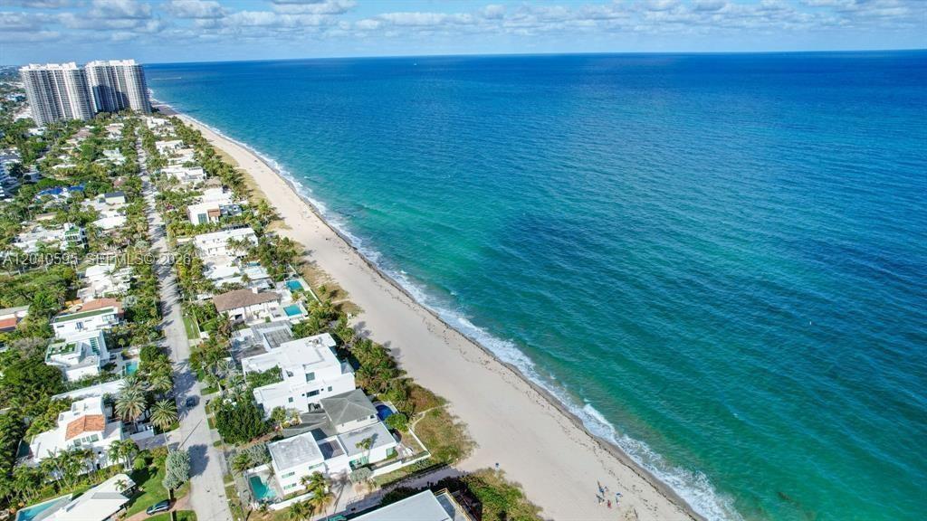 An aerial view shows a sandy beach bordering the ocean next to coastal residential homes — FORT LAUDERDALE, FL