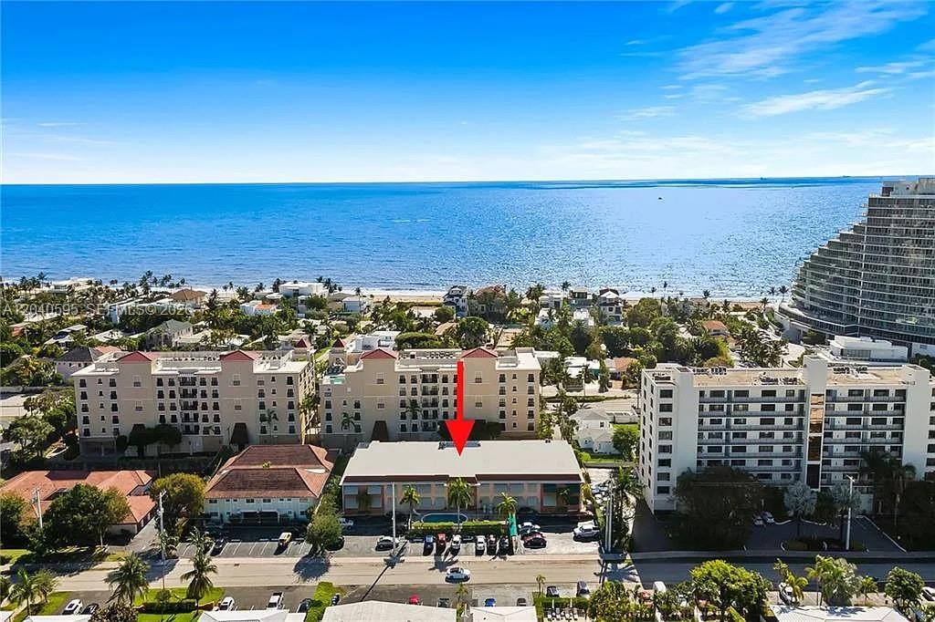 An aerial view shows a low-rise building marked with a red arrow near the ocean — FORT LAUDERDALE, FL