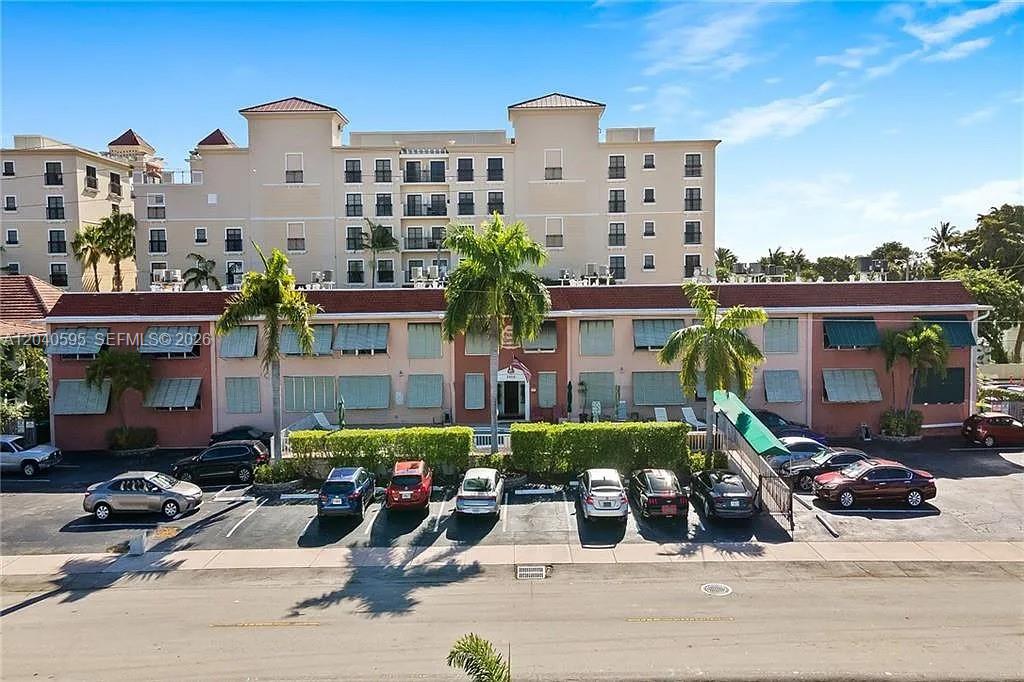 An exterior view of a multi-story apartment building with a parking lot in front — FORT LAUDERDALE, FL