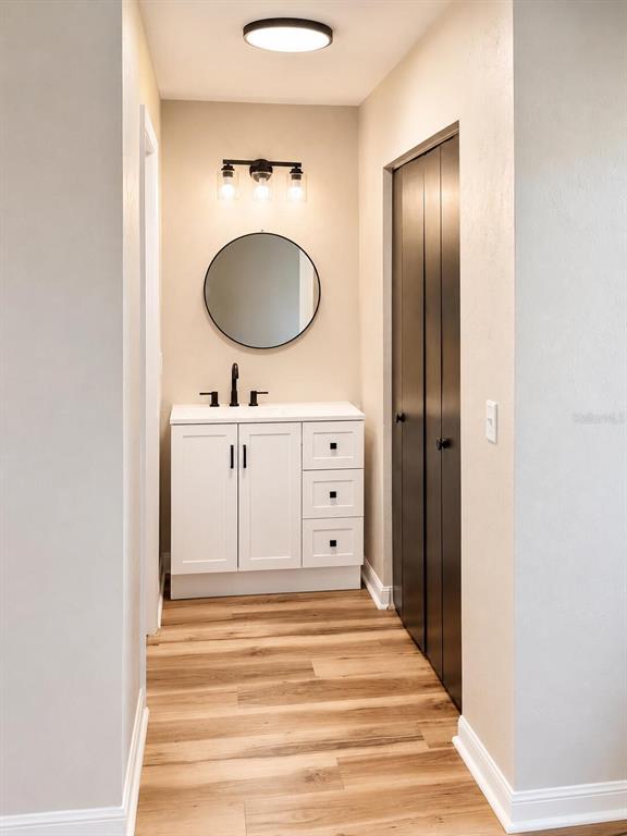 A bathroom features a white vanity, a round mirror, and a dark bi-fold closet door — 3604 NW 51ST TERRACE, GAINESVILLE, FL