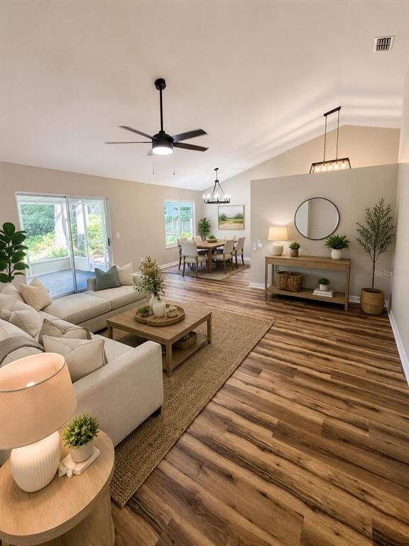 An open-concept living and dining area features vaulted ceilings, wood-look flooring, and neutral decor — 3604 NW 51ST TERRACE, GAINESVILLE, FL