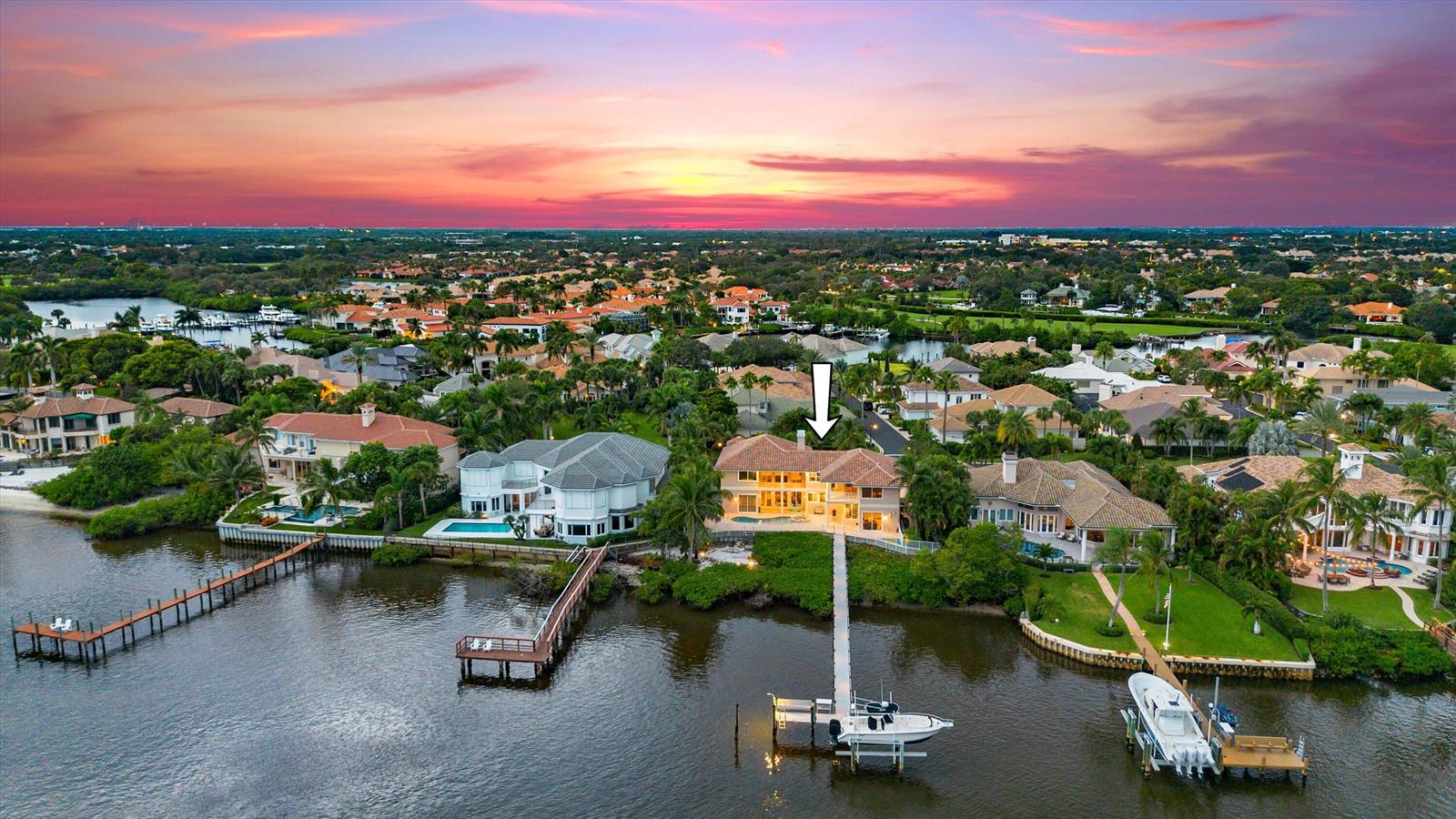 An aerial view of a waterfront house with a private dock and boat at sunset — 3164 Casseekey Island Road, Jupiter FL 33477, JUPITER, FL