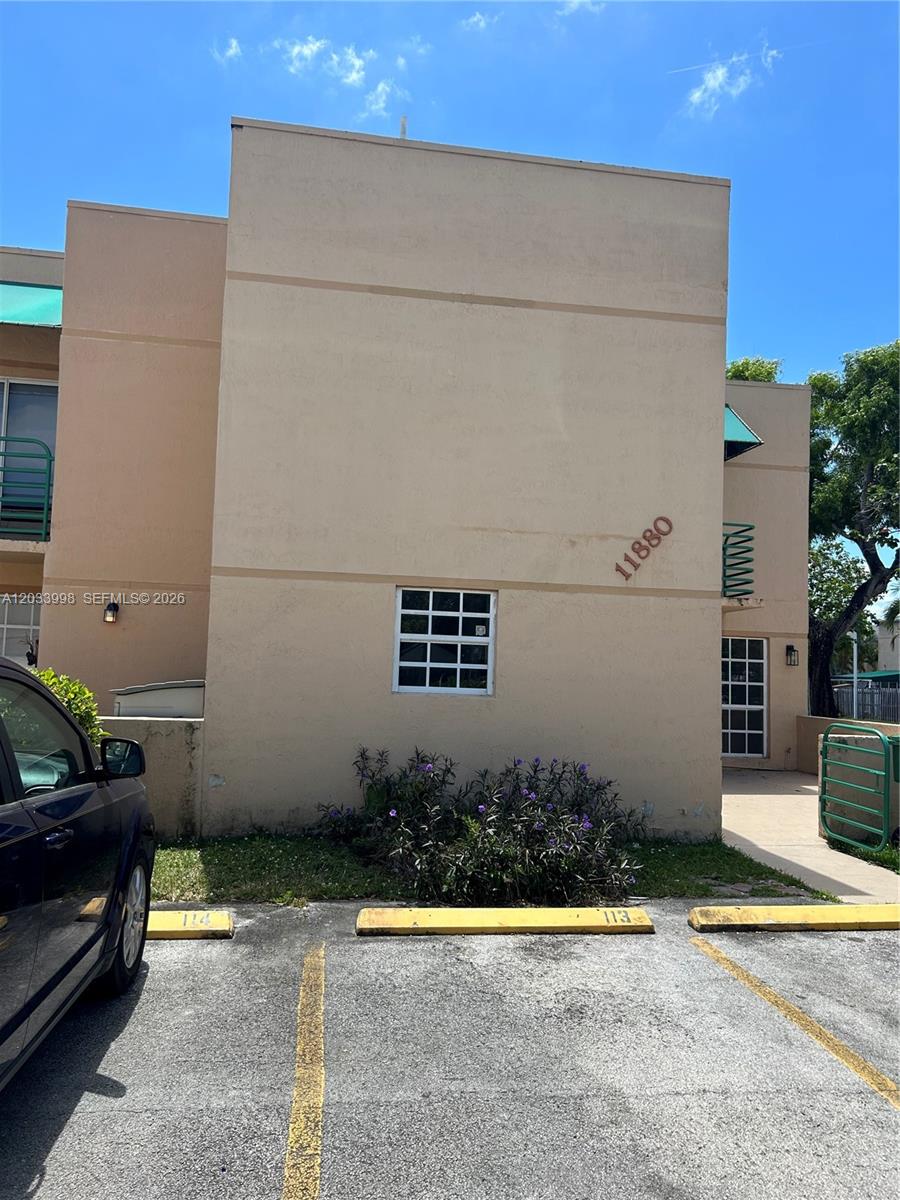 The exterior of a tan two-story building features a small window and parking spaces — 11880 SW 19th Ter # 113, Miami FL 33175, MIAMI, FL