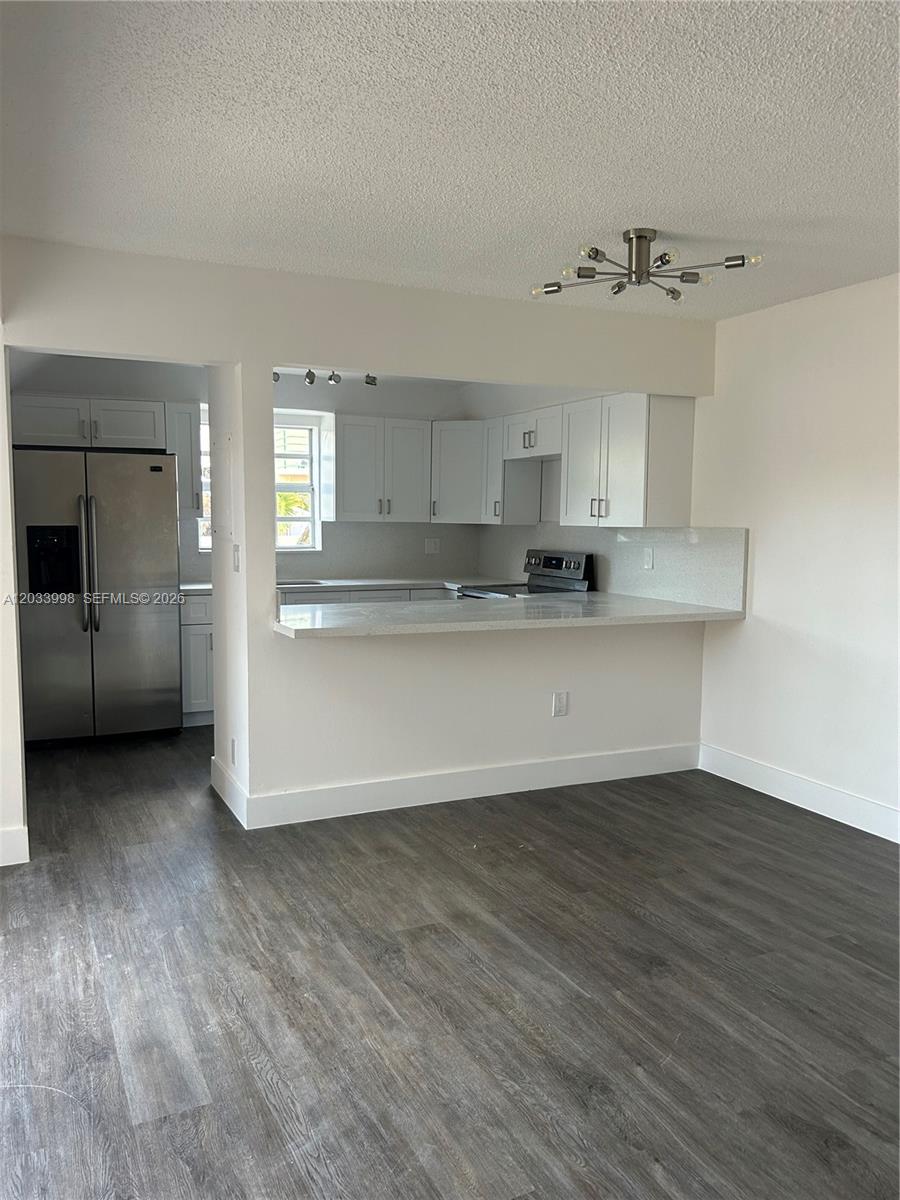A kitchen with white cabinets and stainless steel appliances opens to a living area — 11880 SW 19th Ter # 113, Miami FL 33175, MIAMI, FL