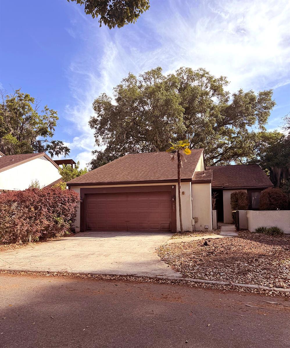 A single-story house with a brown garage door, a palm tree, and large oak trees — 7962 Linkside Drive, Jacksonville FL 32256, JACKSONVILLE, FL
