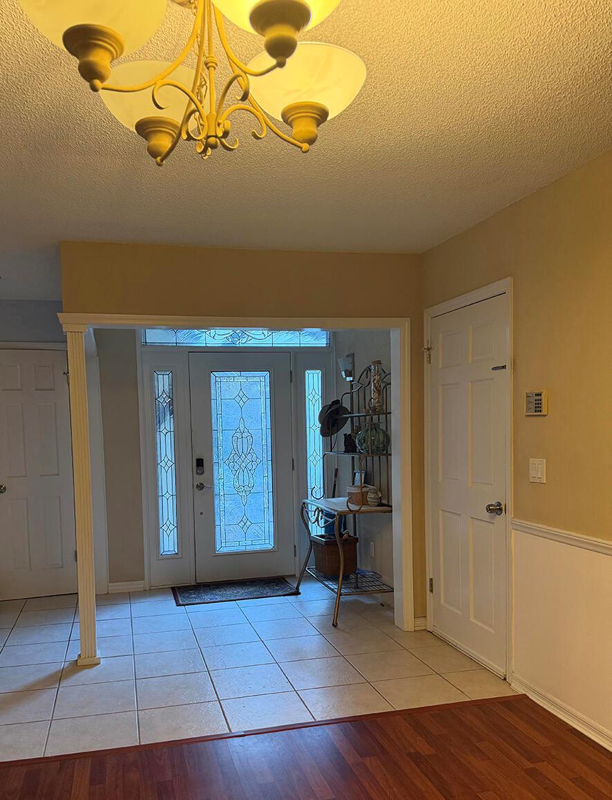 An entryway features a glass-paneled front door, tile flooring, a chandelier, and white trim — 7962 Linkside Drive, Jacksonville FL 32256, JACKSONVILLE, FL