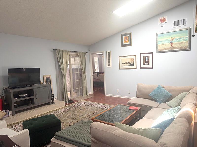A living room features a sectional sofa, a television on a console, and wall art — 7962 Linkside Drive, Jacksonville FL 32256, JACKSONVILLE, FL